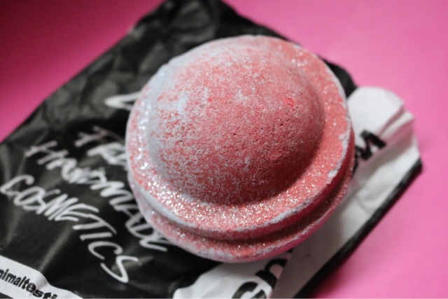 Close up photo of the Space Girl Bath Bomb from Lush on a lush wrapper, on a pink backdrop