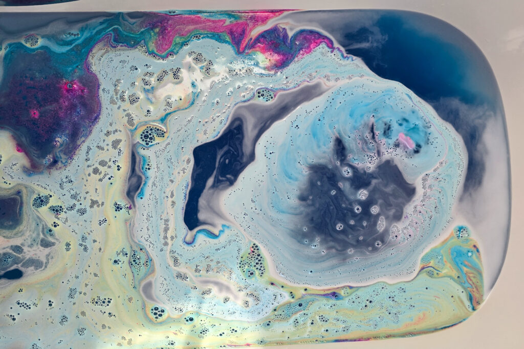 Photo taken by Jordanne / Ofaglasgowgirl of Lush Intergalactic Bath Bomb in the water, fizzing with swirls of blue, yellow and pink plus glitter 