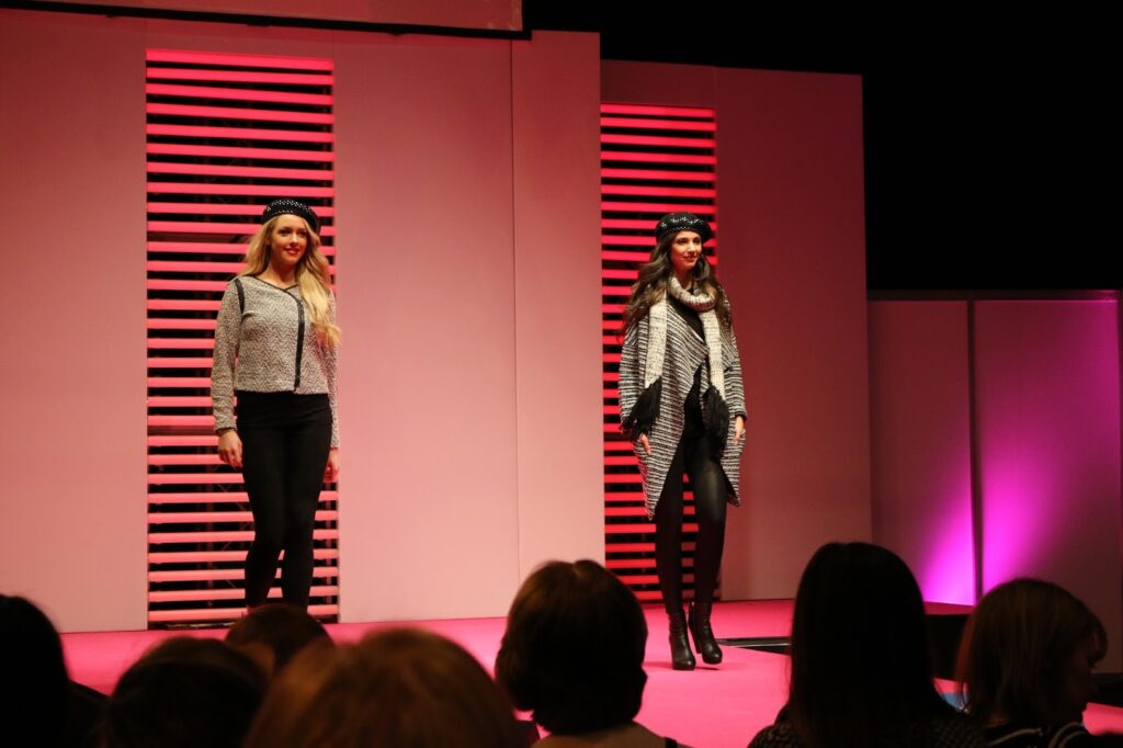 a photo of the fashion cat walk at girls day out show 2015. there are two models walking on the run way wearing winter clothes