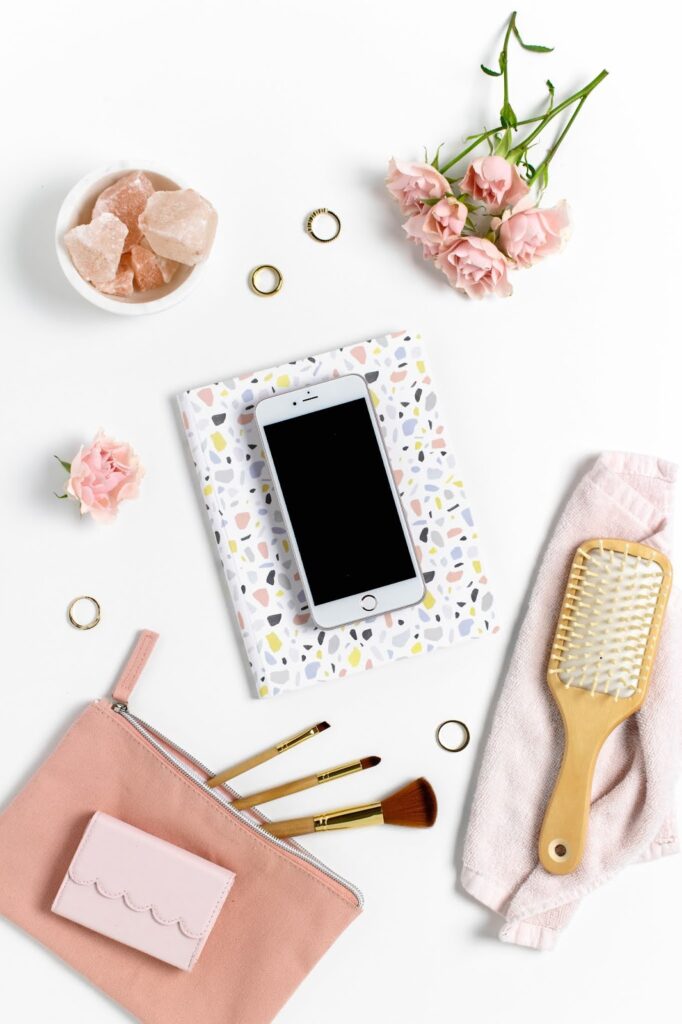 Stock image Birds eye view of a phone on a white table with pink flowers and a notebook