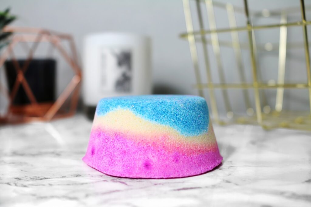 Miss Patisserie Unicorn Hoof on Thelifeofaglasgowgirl.co.uk Close up side photo of the Miss Patisserie Unicorn Hoof sitting on a white marble table top. The bath bomb in pink, yellow and blue with a flat back