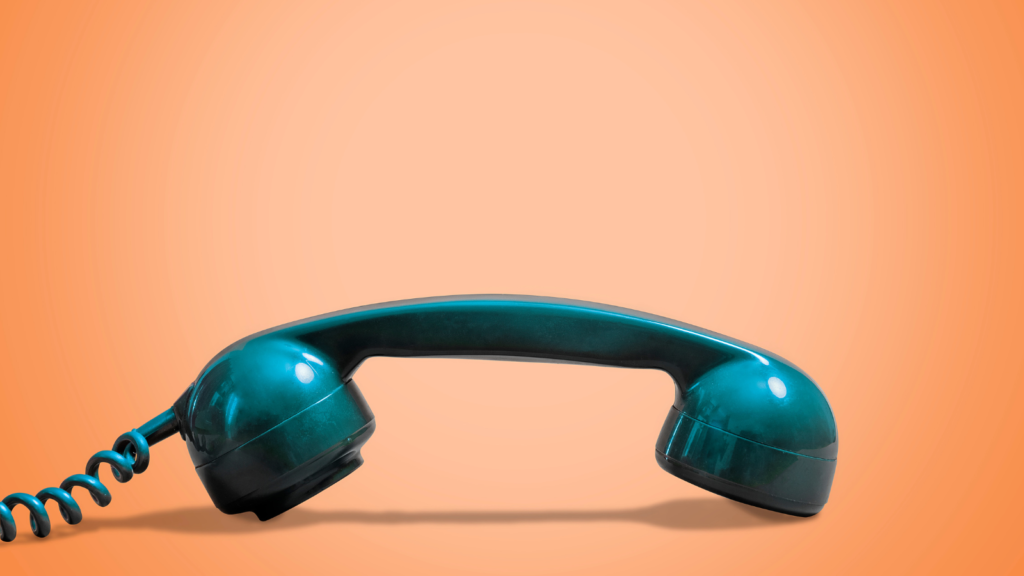 Photo of a green house phone with a green cord on an orange backdrop