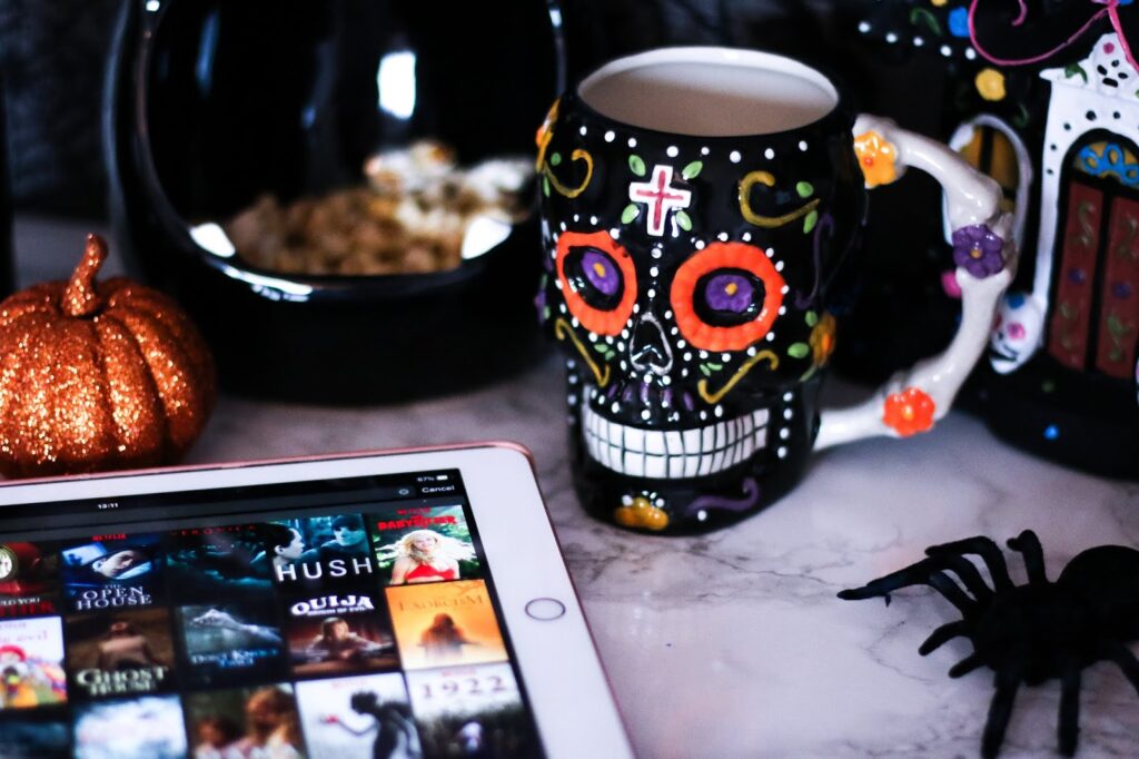 Horror Month: What's On My Watch List - Close up photo of a skull mug next to spider and ipad