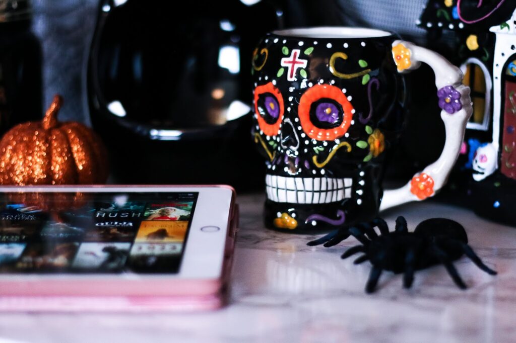 Horror Month: What's On My Watch List - Close up photo of a skull mug next to spider and ipad