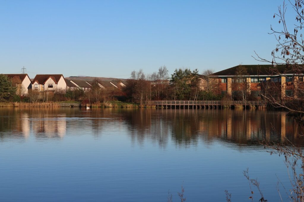 landscape at broadwood loch a landscape photo of broadwood lock with blue skies and deep blue water with houses in the background