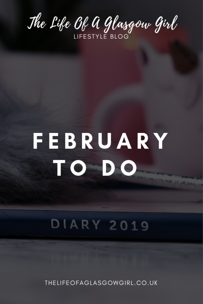 Pinterest image for February To Do List on Thelifeofaglasgowgirl a busyb 2019 diary on a marble counter top with a grey fluffy pen on top of it. There is a white unicorn light in the background and a pink candle.