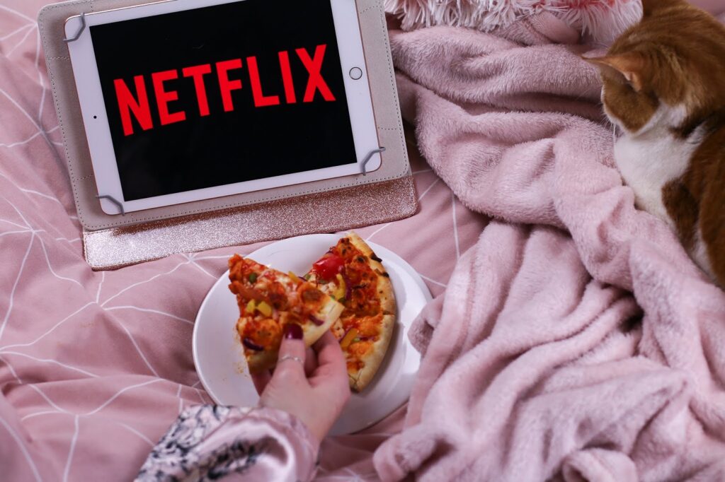 Close up photo of Ofaglasgowgirl reaching for pizza and Netflix on in the background