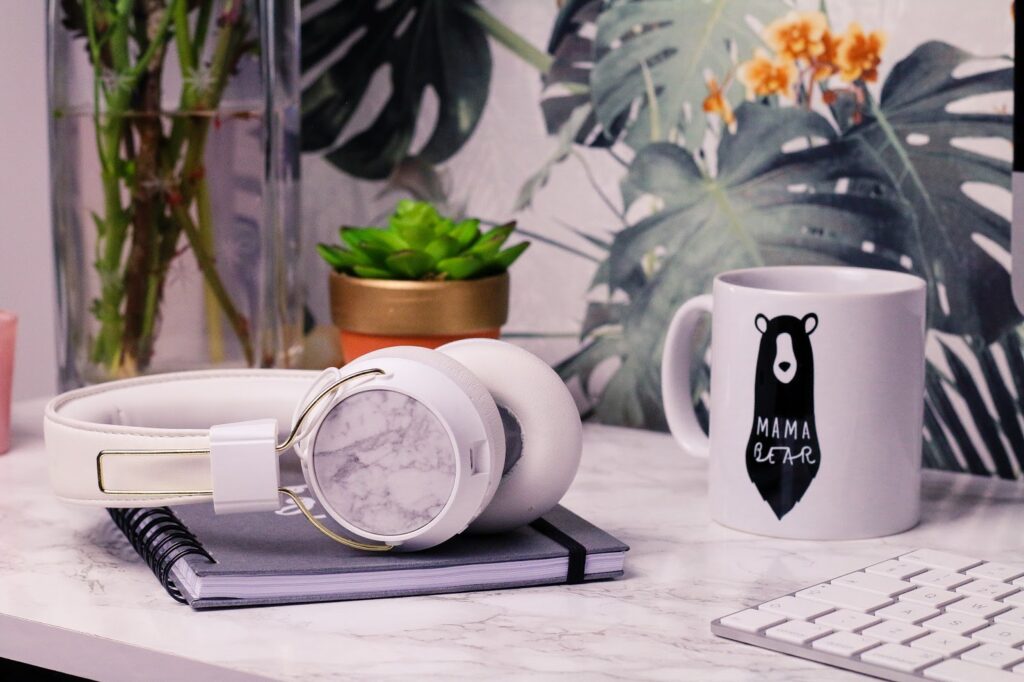 Feel good playlist - Spotify playlist to lift your mood and spirits. Songs guaranteed to lift your mood on Thelifeofaglasgowgirl.co.uk Close up of white sudio headphones on a white marble desk with a white mug next to them and flowers in the background