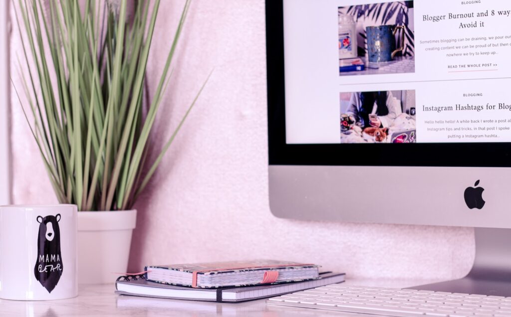 Photo of a mac on a marble desk with a plant in background