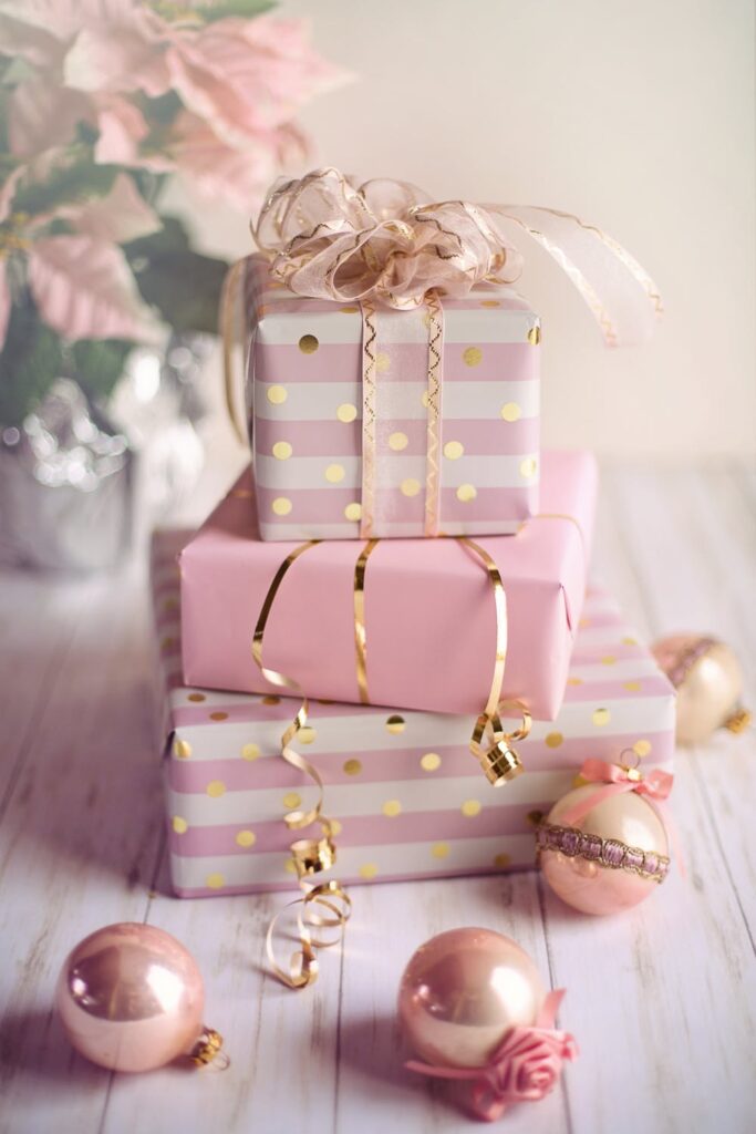 Stock photo from pexels by Jill Wellington of three christmas presents wrapped in pink wrapping paper sitting an a white desk