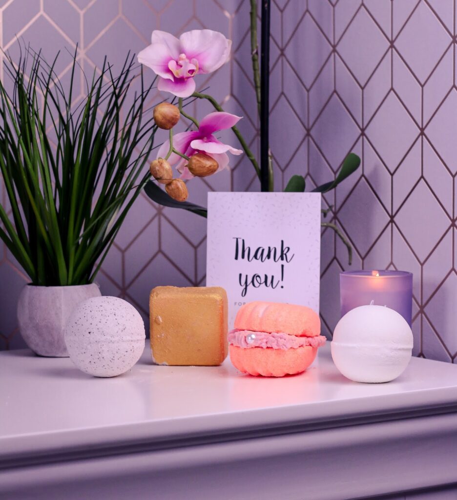 Close up photo of 5 bath bombs from Gaea ontop of a white bedside table