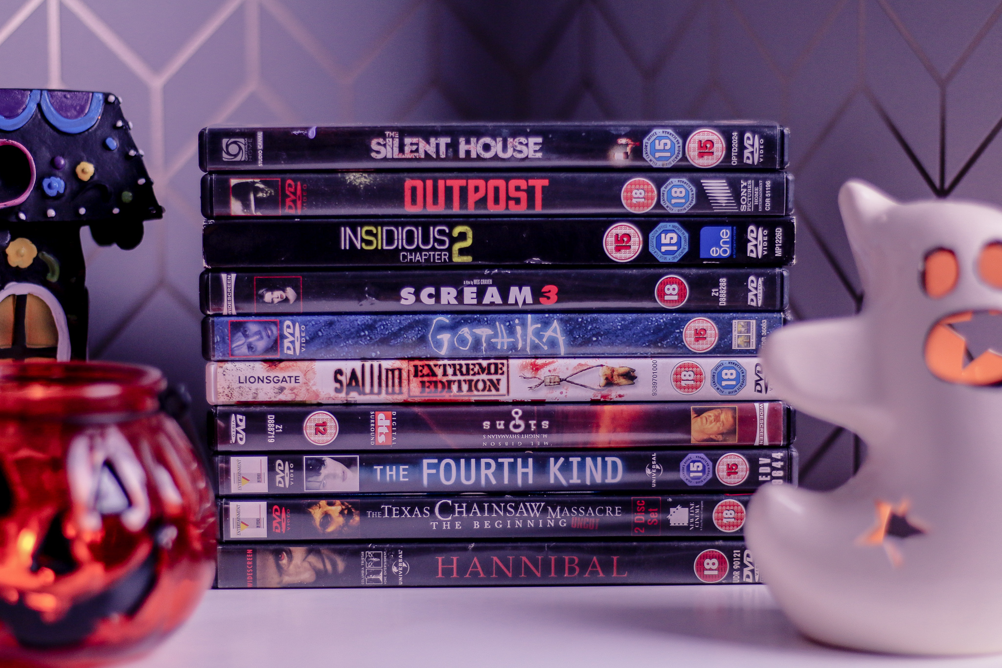 What I'm watching in October - What's on my to watch list in October on Thelifeofaglasgowgirl.co.uk Close up of 10 horror movie dvds stacked on top of each other on a white bed side table