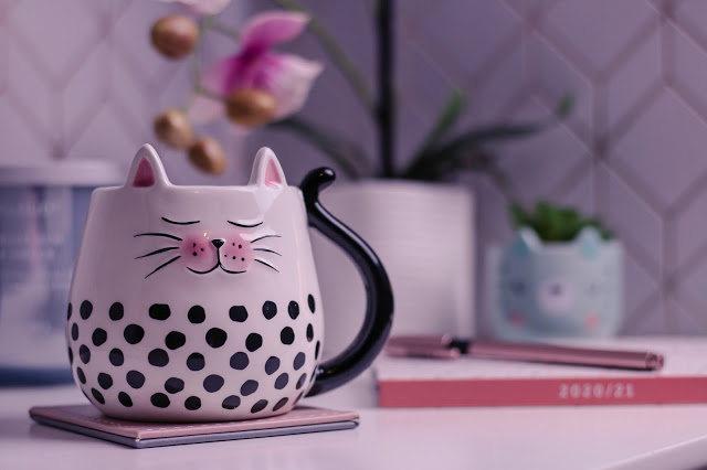 Close up photo of a cat mug on a white bedside table