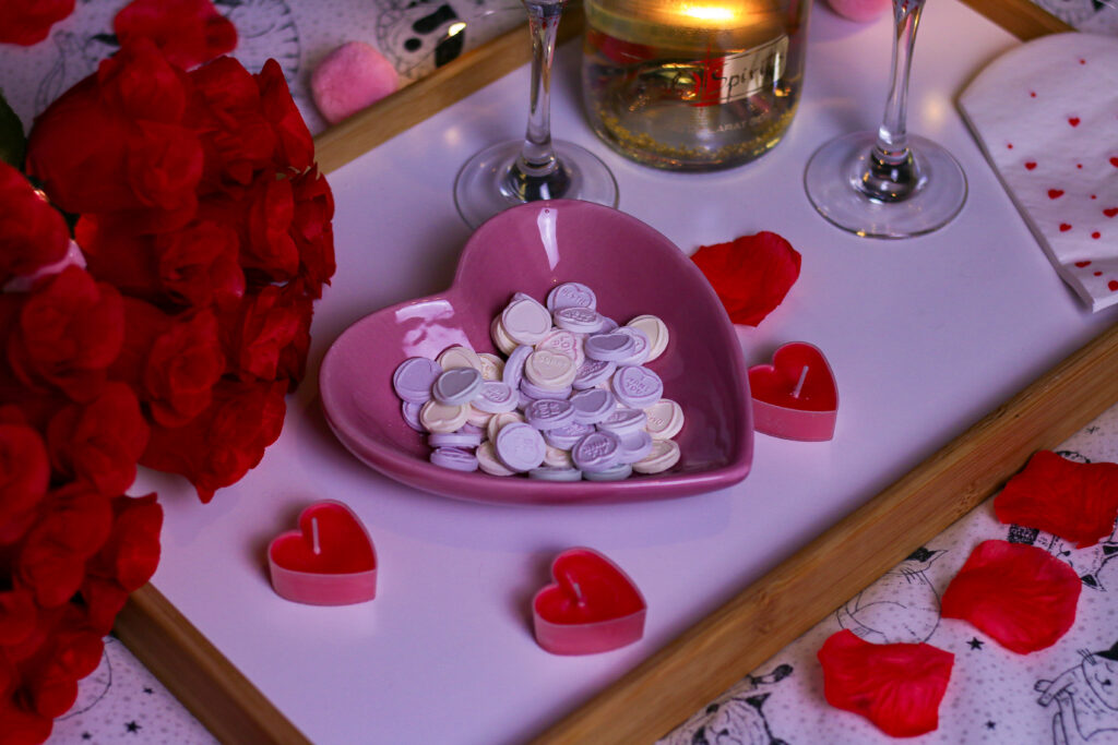 Valentine's date night ideas - Close up photo of a pink heart bowl with love heart sweets in it