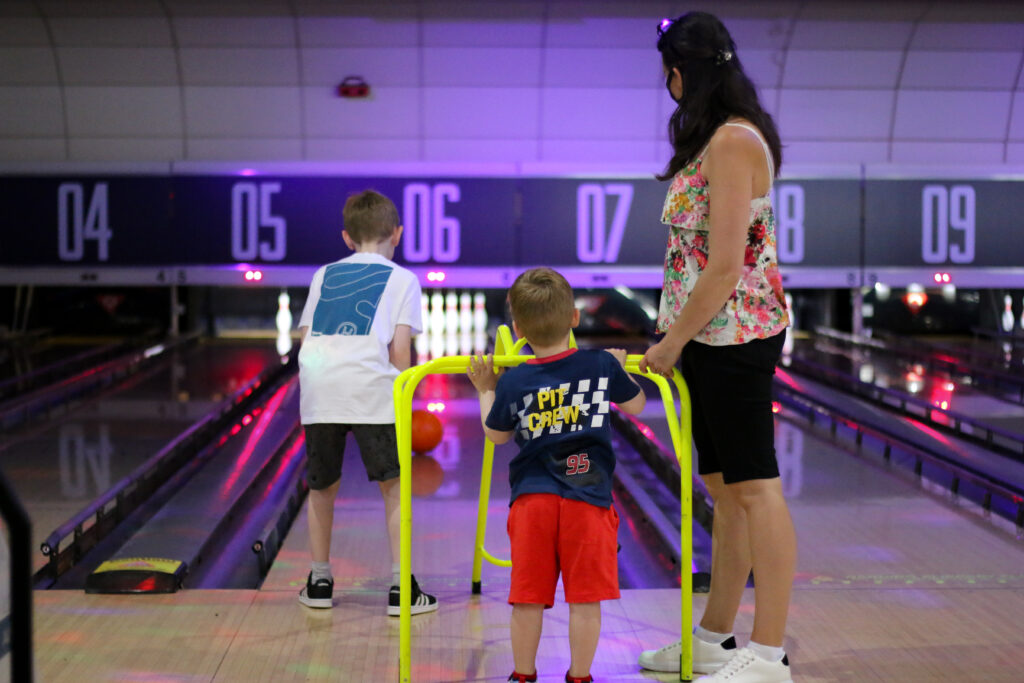 July Roundup - Photo of two children and one adult playing bowling