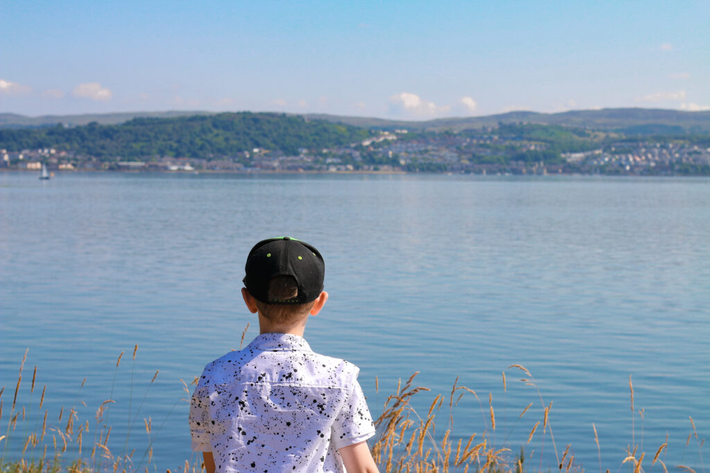 Close up of young child looking out over water at Kilcreggan