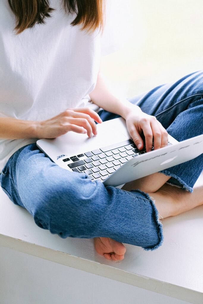 September Advertisers - Stock photo from pexels by Anna Shvets of a woman using a silver laptop wearing blue jeans and a white top