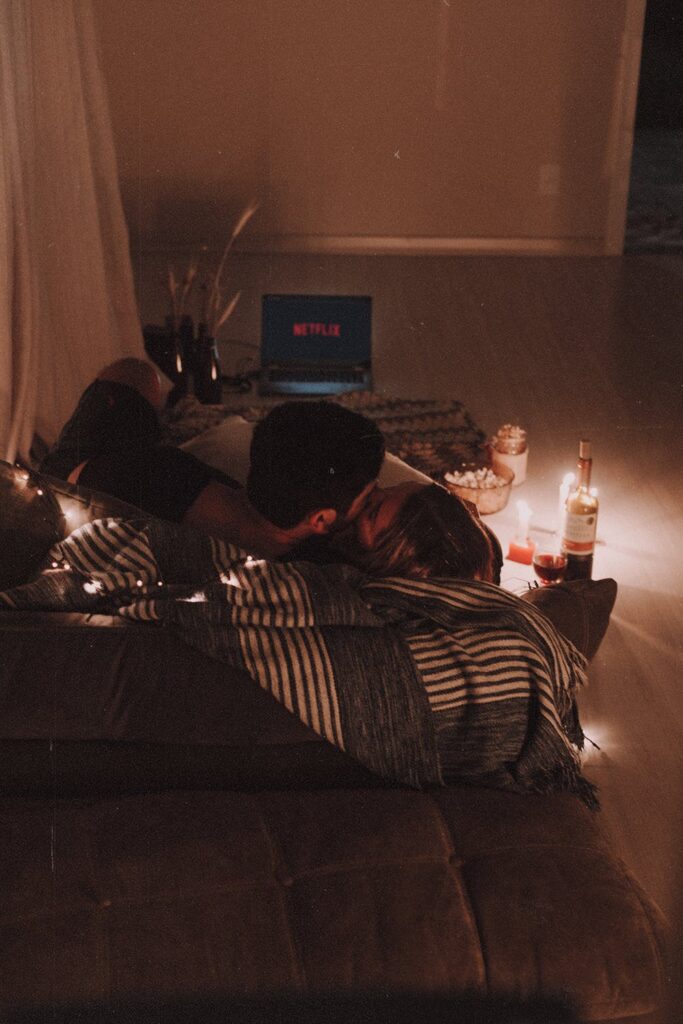 Stock Photo from pexels by Edward Eyer of a man and woman in a bed cuddling, watching Netflix