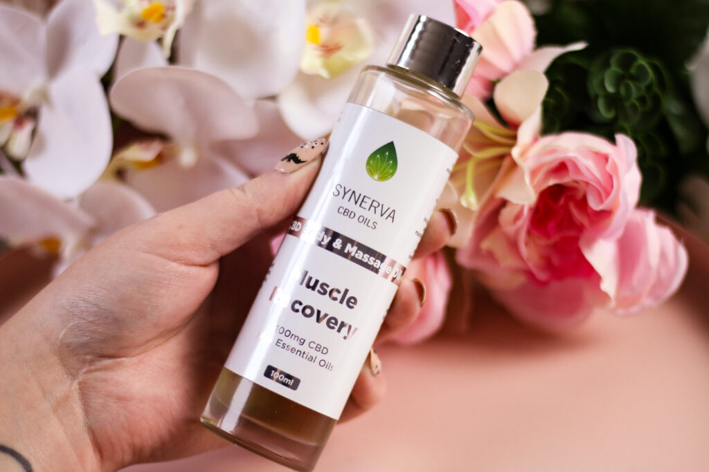 A close up photo of a woman holding a bottle of the body and massage oil muscle recovery.