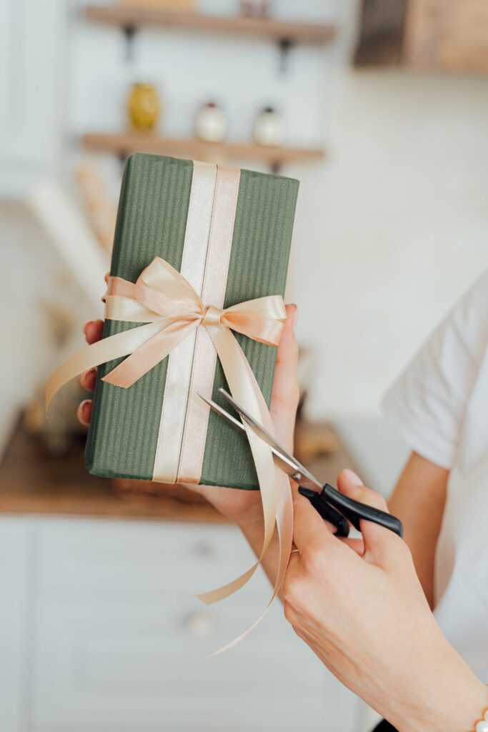 5 Top Tips to Stay Organised With Birthdays All Year Round - Stock photo on pexels by Anthony Shkraba of a woman holding a gift wrapped green present with a cream bow around it