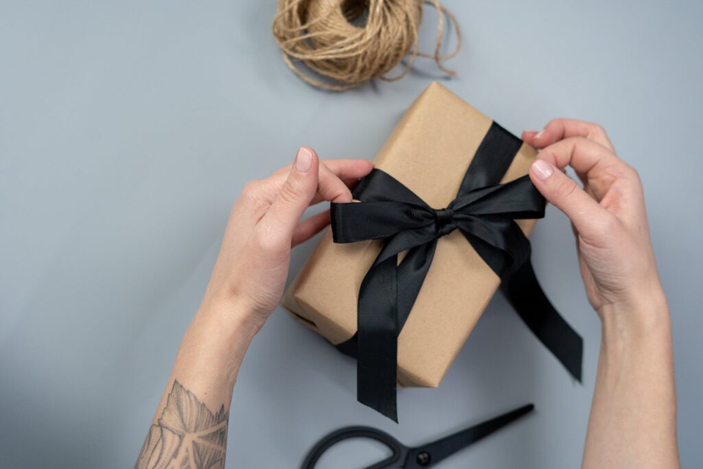 5 Top Tips to Stay Organised With Birthdays All Year Round - Stock photo from pexels by cottonbro of someone wrapping a present with brown paper and a black bow