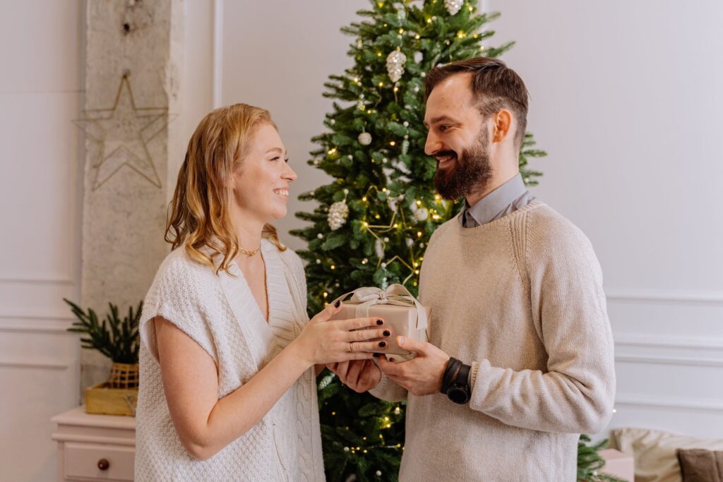 stock photo from pexels by Anthony Shkraba of a woman with blonde hair wearing a white knit top giving a man with brown hair and a caramel knit jumper a gift