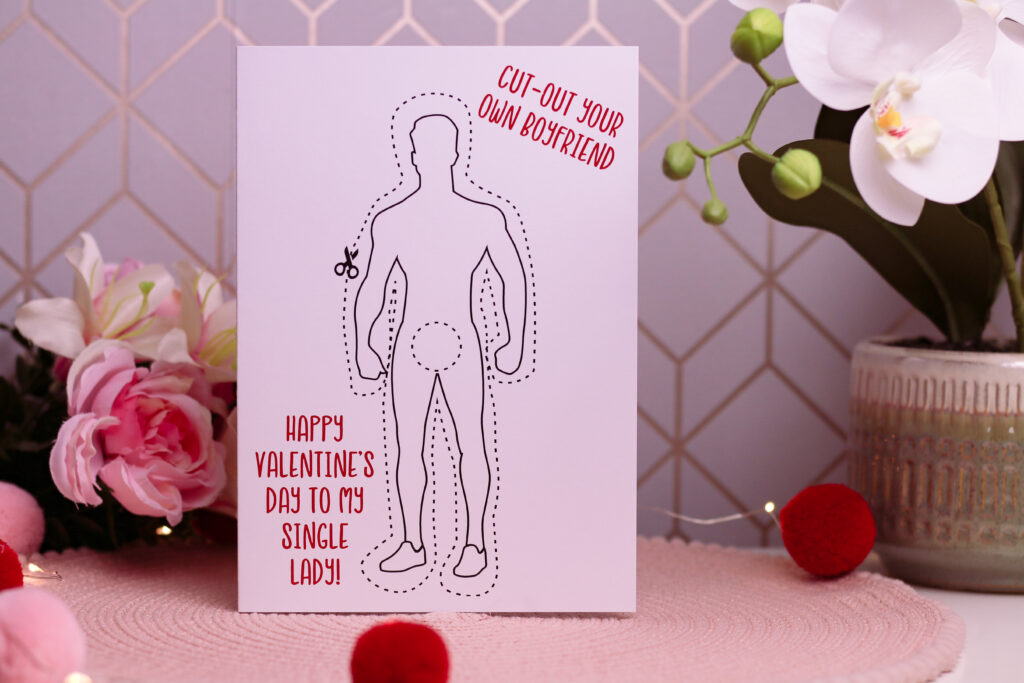 Gifts to Make Valentine's Day the Best - close up photo of a card from Love Layla that has the image of a cut out man on it with "cut-out your own boyfriend. Happy Valentine's Day to my Single Lady" written on it