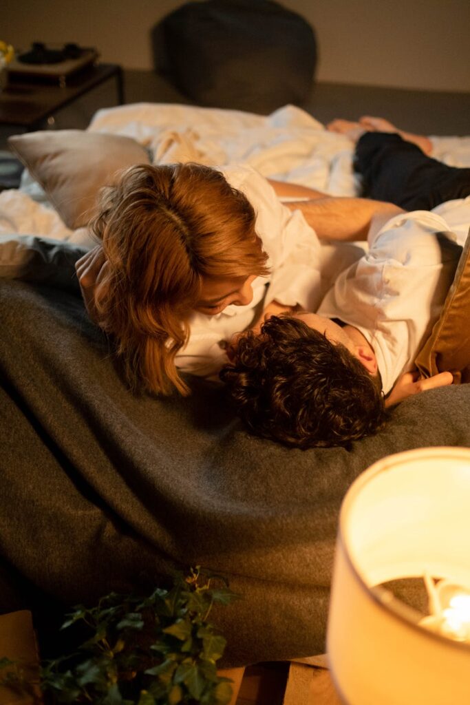 Stock photo from pexels by Cottonbro of a couple laying in bed, laughing with each other for Valentine's Day
