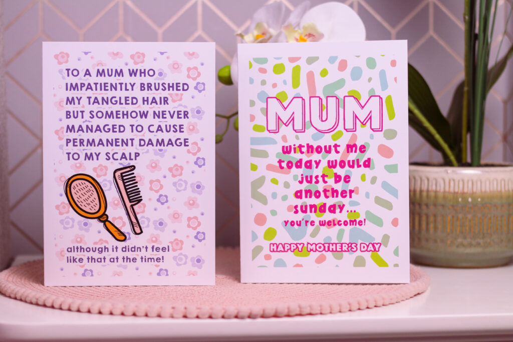 Close up photo of two Mother's Day cards from Love Layla Designs. The first card reads "To a mum who impatiently brushed my tangled hair but somehow never managed to cause permanent Damage to my scalp" The second card reads "Mum, without me today would just be another Sunday, you're welcome!" that can be used in the Gift Basket Ideas for Mother's Day