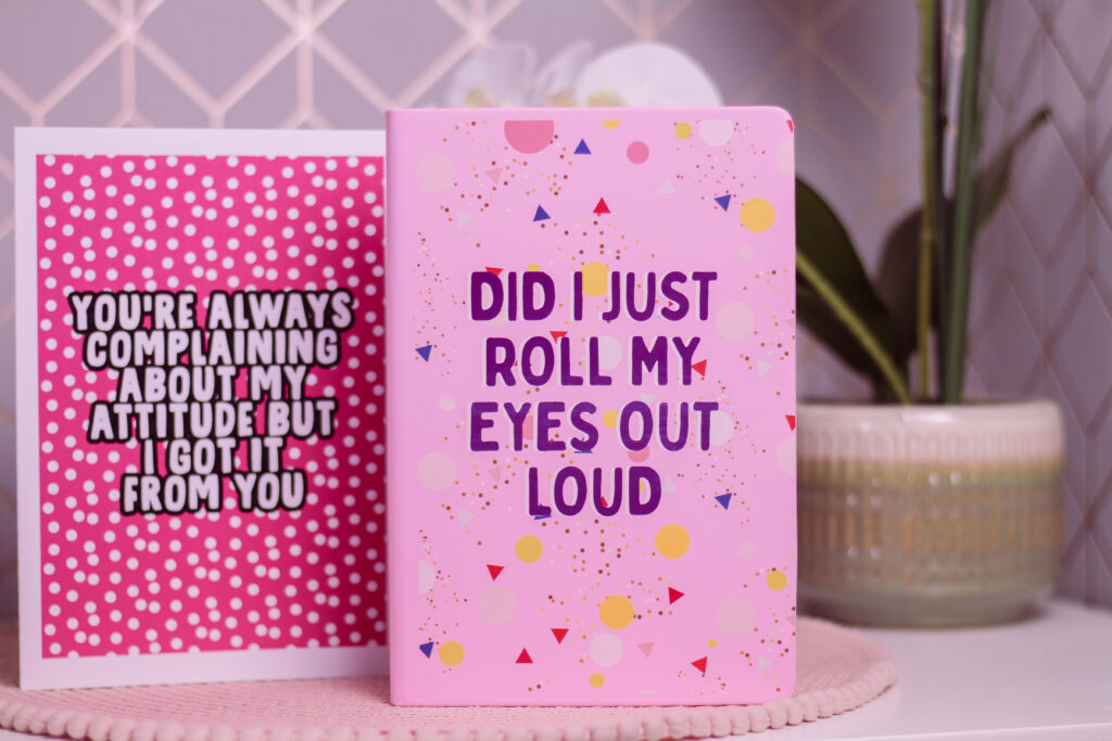 Close up of a pink notebook from Love Layla Designs that has "Did I Just Roll My Eyes Out Loud" in purple