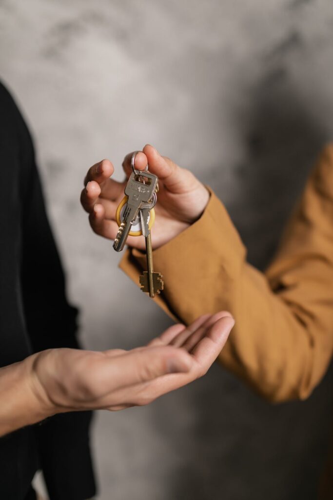 Stock photo from pexels by Alena Darmel of a woman handing house keys to someone - Tips for Landlords