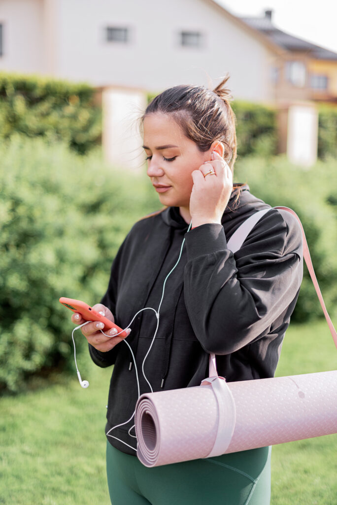 Stock photo from pexels by Mikhail Nilov of a Woman in Black Jacket Holding a Smartphone with Earphone - The Perfect Self-Care Activities for Spring