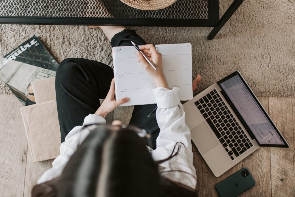 Stock photo from pexels by Vlada Karpovich of a Faceless lady with notebook and laptop on floor at home
