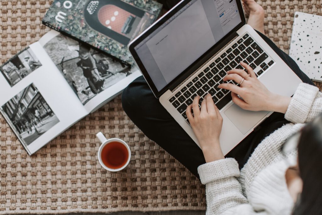 Stock photo from pexels by Vlada Karpovich of a young businesswoman using laptop while drinking tea at home