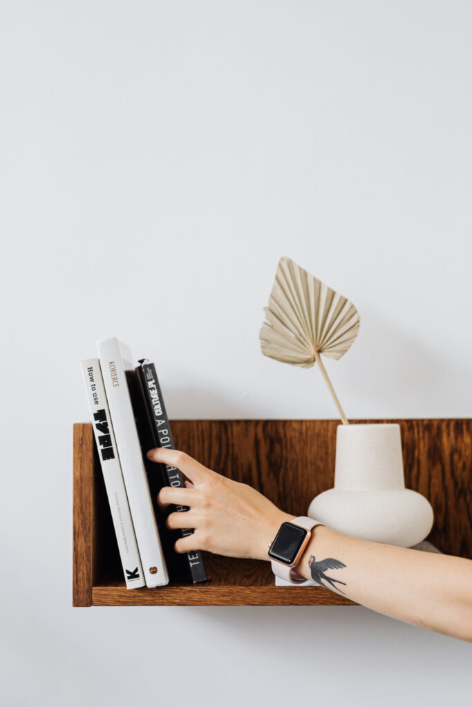 Stock photo from pexels by Karolina Grabowska of a wooden shelf on a wall with three books on it