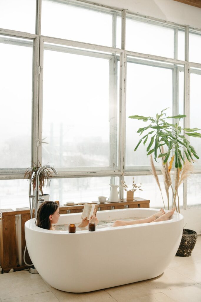 Stock photo from Pexels by Yaroslav Shuraev of a woman laying in a bath reading a book
