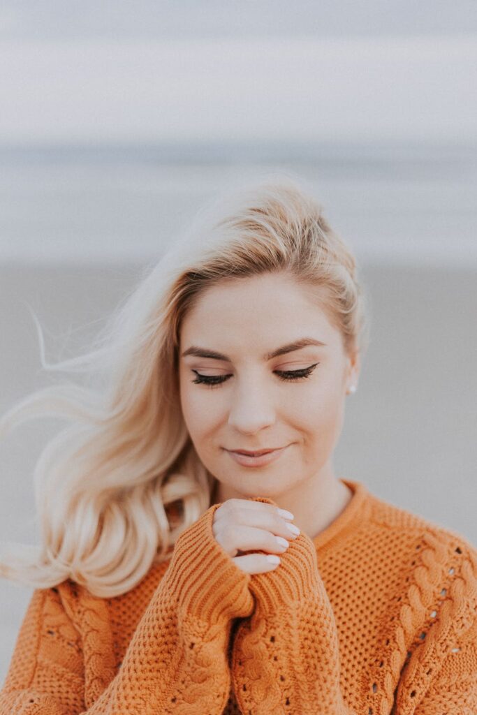 Stock photo from Pexels by Julia Avamotive of a woman in an orange jumper, blond hair flowing in the wind