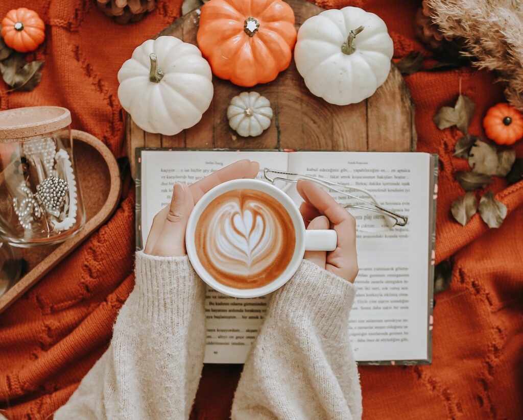 Stock photo from pexels by Melike Benli of woman holding a mug with coffee in it with an orange blanket in background