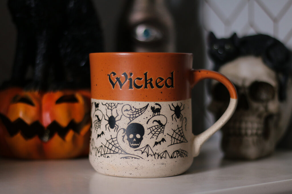 Taking a Look at My October To-Do List main blog post photo - Close up of an orange and beige mug with black images of skulls, bats and spiders. There is black text reading "Wicked"