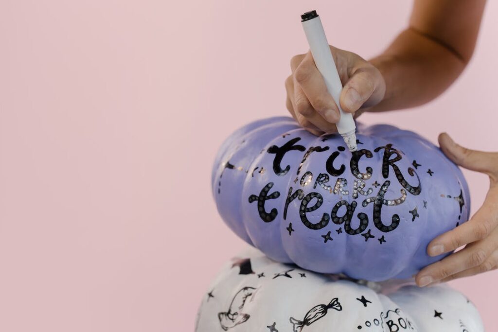 Stock photo from pexels by Cotton bro of two pumpkins on a table. One pumpkin is purple with black text reading "Trick or Treat" and one pumpkin is white with black text reading "Boo"