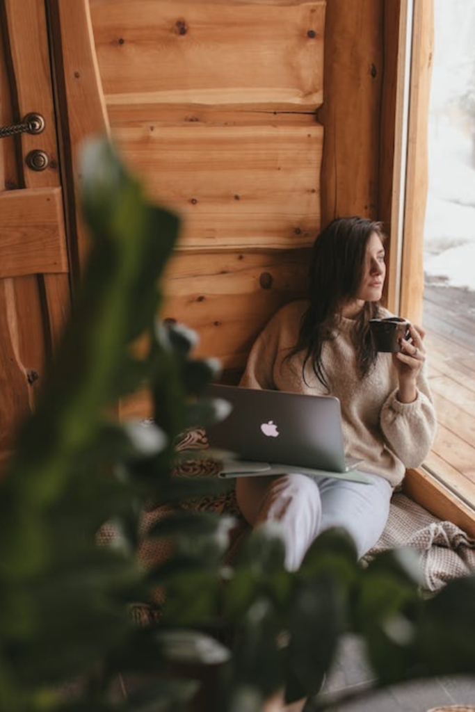 Stock photo of woman on laptop next to an open window