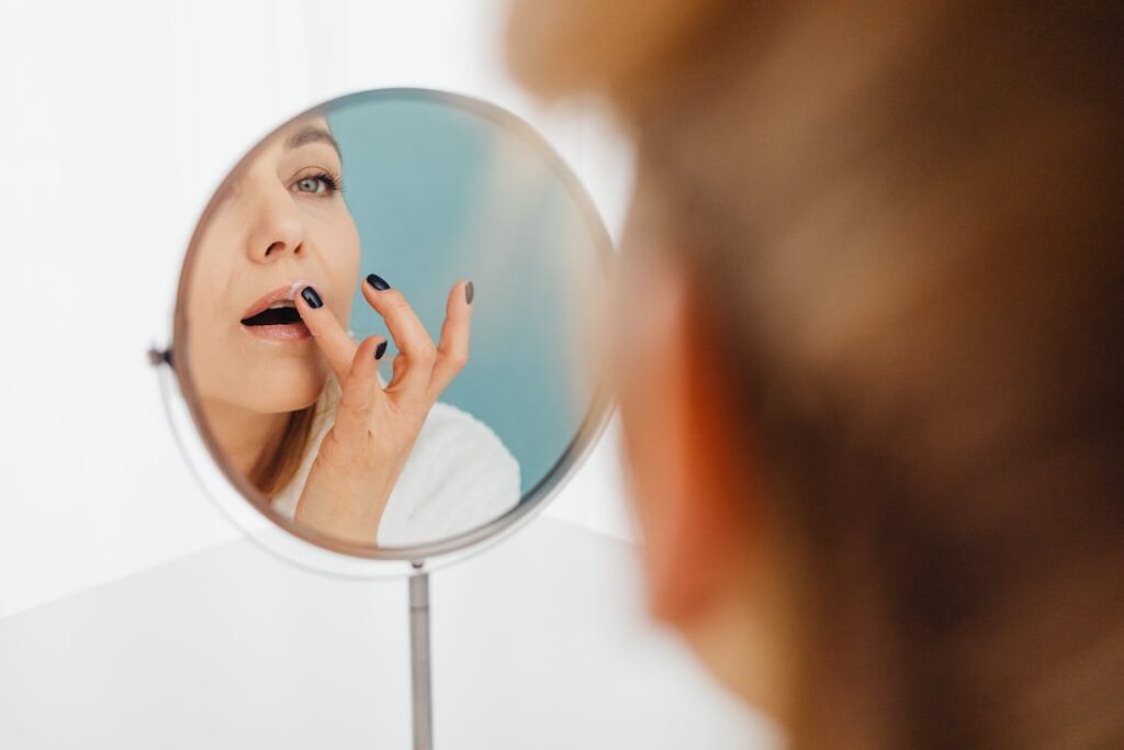 Stock photo from pexels by Karolina Grabowska of a woman applying lip balm in a mirror