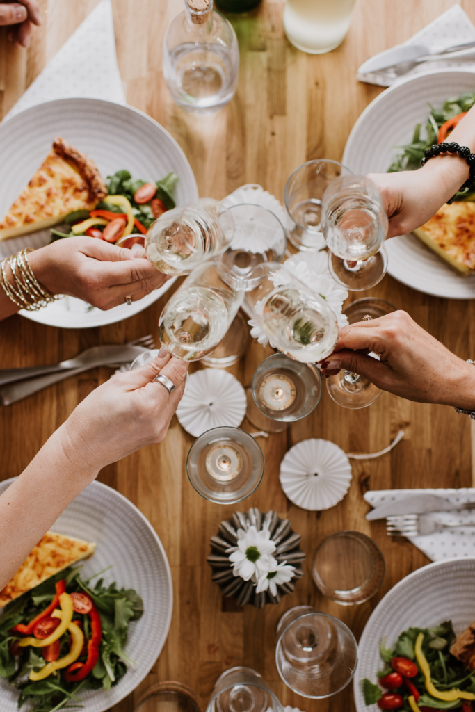 Stock photo from Canva by Knape at Getty Images Signature of people clinking wine glasses together over a dinner table