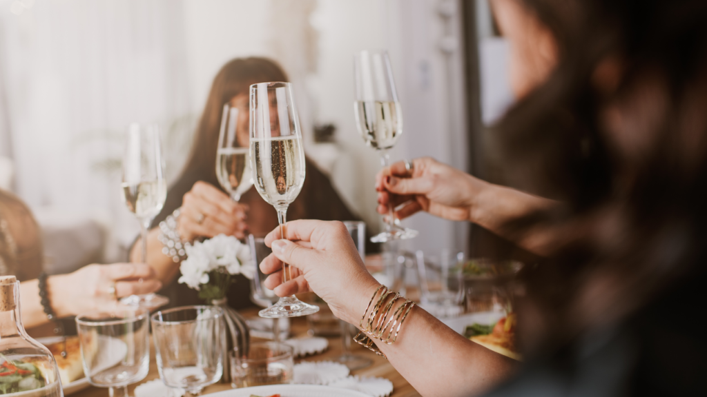 Stock photo from Canva by Knape at Getty Images Signature of people clinking wine glasses together over a dinner table
