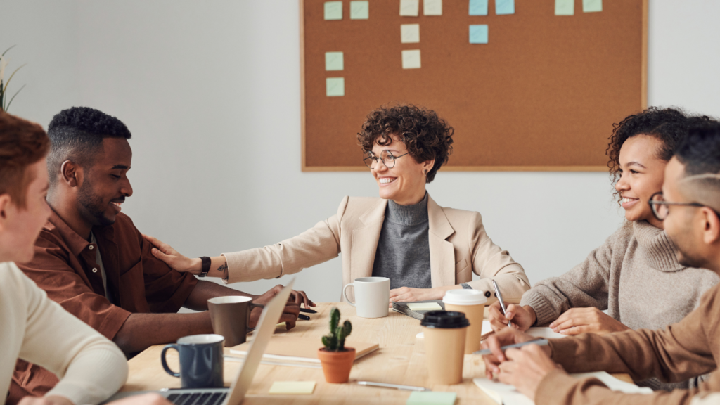 Stock photo from Pexels by Fauxels of 5 employees sitting at a desk talking