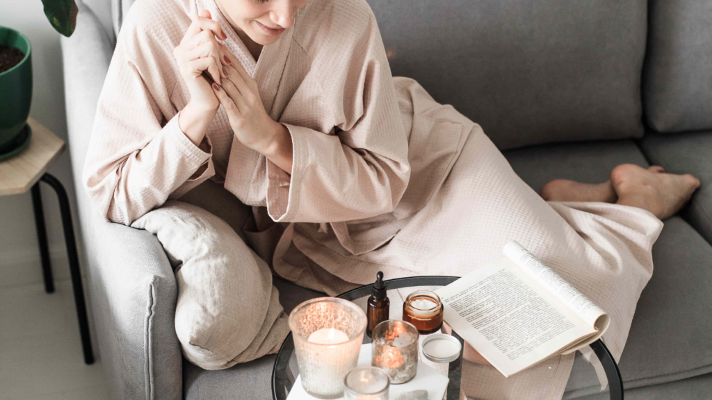 Stock photo from Canva by Diana Akhmetianova at Studio Russia of a woman with towel on her head and brown dressing gown laying on a grey couch reading a magazine