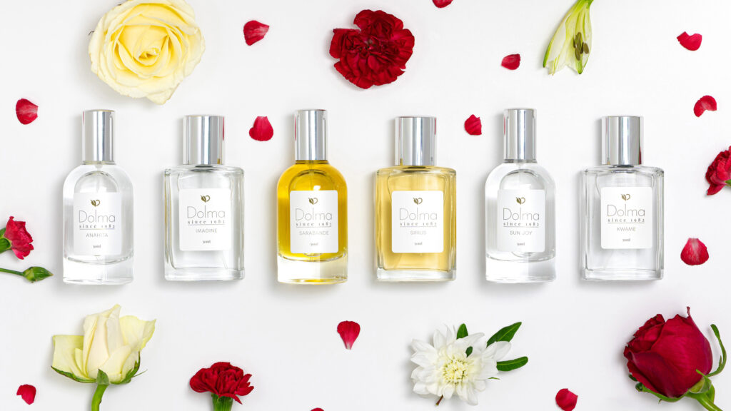 Birds eye view of 6 Dolma Perfumes on a white background with red and yellow roses heads