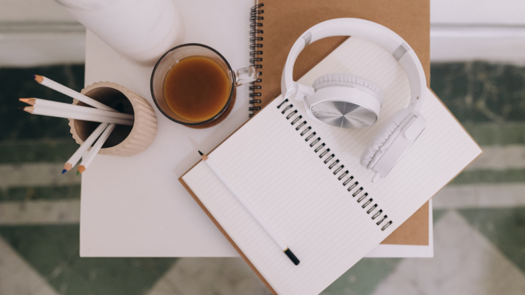 Stock photo from Canva by Carolin Voelker at Corelens of a notebook open on a table with white headphones on top