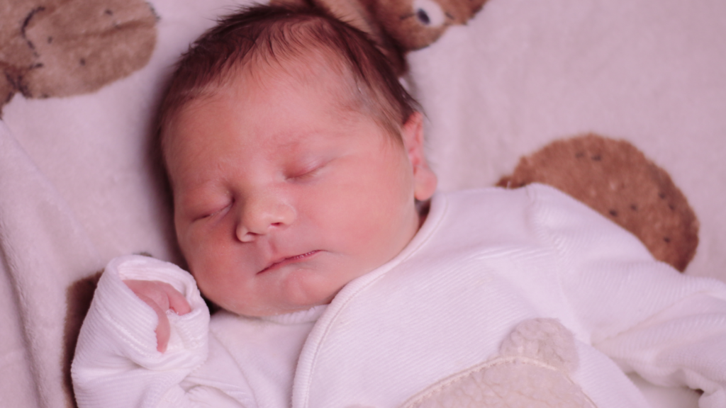Birds eye view of Ofaglasgowgirl's new baby boy wearing a white onesie with a brown bear on it