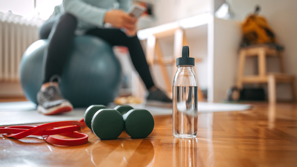 Stock photo from Canva by mixetto at Getty Images of weights and a water bottle on a wooden floor
